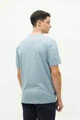 Remera celeste de manga corta con bolsillo en el pecho y estampado con palmera y texto.