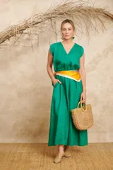Vestido largo verde esmeralda de lino, con escote en V, mangas cortas con volados y bolsillos laterales. Incluye un pañuelo de seda estampado en tonos naranja y blanco a modo de cinturón.