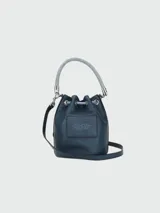 Bolso bombonera Marc Jacobs modelo The Bucket, color gris con logo estampado en negro, asa de mano trenzada y correa de hombro ajustable.