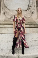 Vestido largo con estampado floral en tonos fucsia, negro y dorado. Tiene escote en V cruzado, mangas al codo, elástico en la cintura y lazo. Incluye viso al tono con breteles regulables y detalle de puntilla en el escote.