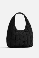 Bolso de hombro negro fabricado en tejido técnico acolchado con diseño geométrico. Tiene un compartimento principal con cierre mediante imán, un bolsillo plano y un bolsillo con cierre mediante cremallera en el interior.