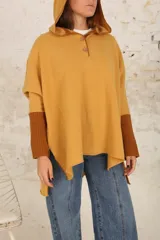 Poncho con capucha color mostaza, con mangas largas color marrón.