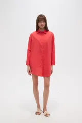 Camisa blanca de algodón con cuello clásico, corte holgado, cierre frontal con botones y mangas largas.