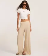 Pantalón largo color beige, de poliéster texturizado, con cintura elástica y bolsillos laterales.