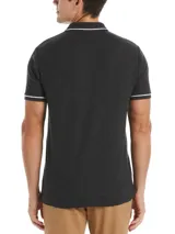 Polo gris oscuro de piqué de algodón con cuello clásico, tapeta de dos botones y manga corta con ribete blanco. Tiene un bolsillo de parche en el pecho izquierdo con el logo bordado de la marca.