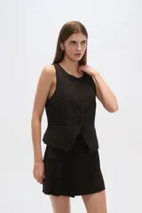 Chaleco negro con escote redondo, sin mangas, corte al cuerpo y cierre frontal con botones. Presenta un bolsillo de ojal en el frente.