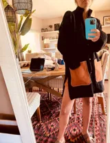 Saco tipo tapado de lana negro con bolsillos de cuero marrón, botones al frente y tajos a los costados.