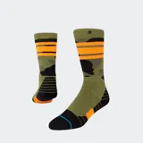 Medias deportivas tipo crew de Stance, con diseño de camuflaje militar en tonos verde oliva y negro, acentos en naranja brillante y detalles de rayas naranjas en el borde superior.