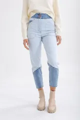 Pantalón de jean celeste con cintura alta y corte recto. Presenta un diseño color block con secciones en denim de tono más oscuro en la cintura y en la parte inferior de las piernas.