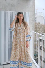Vestido largo color beige con estampado abstracto en tonos marrones y azules, con cuello mao, mangas largas con puños elásticos y cierre frontal con botones.