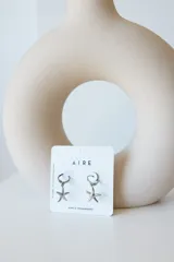 Par de aros dorados con forma de estrella de mar colgando de un aro pequeño.