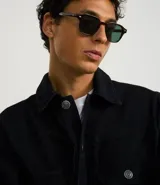 Campera trucker masculina de jeans negro, con cuello inglés, manga larga ajustada, cierre abotonado, bolsillos delanteros y sin estampa.