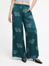 Pantalones palazzo de color verde con estampado de figuras abstractas en blanco, de corte amplio.