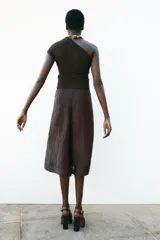 Pantalón culotte color marrón oscuro, de tiro alto con pliegues delanteros y tejido semitransparente efecto arrugado. Tiene forro interior y cierre lateral con cremallera oculta.