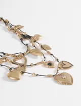 Collar de múltiples hebras negras con dijes colgantes de metal plateado en forma de corazón, algunos lisos, otros con textura o incrustaciones de piedras negras y transparentes.