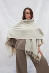 Ruana color crudo con rayas verticales finas en beige y flecos en el borde inferior.