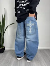 Pantalón de jean celeste de corte ancho con bordado de cruz en el bolsillo trasero.