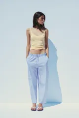 Pantalón tipo barrel con rayas verticales celestes y blancas, tiro medio y cintura elástica ajustable con lazo. Tiene bolsillos laterales y falsos bolsillos de vivo en la espalda.