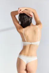 Conjunto de ropa interior color crema, compuesto por un corpiño de encaje con breteles finos y una bombacha tipo colaless con detalle de encaje en la cintura.
