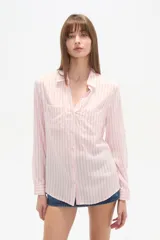 Camisa de viscosa color crema con finas rayas verticales negras, corte al cuerpo, cuello camisa y dos bolsillos frontales con tapa. Posee botones frontales y mangas largas con puño.