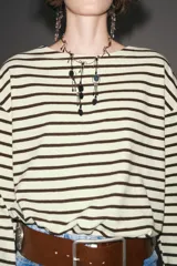 Camiseta de manga larga a rayas horizontales blancas y negras, con cuello redondo y bajo con aberturas laterales.