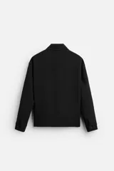 Sobrecamisa negra de corte cuadrado con cuello solapa, manga larga con puños abotonados, bolsillos de parche en el pecho, bolsillos laterales y cierre frontal con botones.