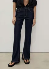 Pantalón de jean azul oscuro, tiro medio, corte flare con aberturas en el bajo y cinco bolsillos.