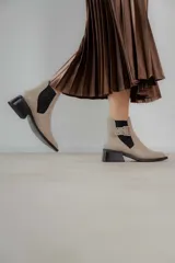 Botines Chelsea color beige con elásticos laterales negros, punta cuadrada, detalle de hebilla lateral y tacón bloque bajo.