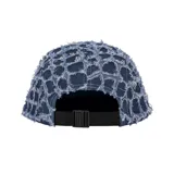 Gorro tipo camp cap de denim azul con diseño deshilachado y logo de Supreme en el frente.