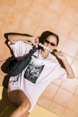 Bolso tipo cartera de nylon con diseño plisado y estampado abstracto en tonos claros.