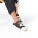 Zapatilla urbana negra con cordones blancos y suela blanca.