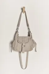 Bolso mini de cuero desgastado color beige claro, con cierre magnético plegable, monedero forrado y bolsillos interiores. Incluye correa de hombro extrapole.