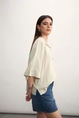 Blusa negra de lino con cuello polo y mangas cortas amplias.