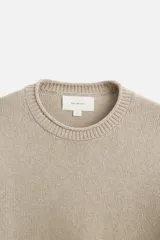 Jersey color beige de punto con cuello redondo y manga larga.