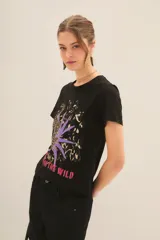 Remera color crudo de algodón con estampado de leopardo, hojas de palma y texto 'Rock in the wind'.