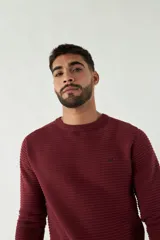 Sweater mostaza de punto con cuello redondo, mangas largas y logo bordado en el pecho. Corte slim fit.