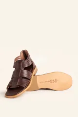 Sandalia de cuero color chocolate con tiras entrecruzadas y cierre trasero con cremallera.