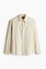 Camisa color crema en mezcla de lino y algodón, de corte regular fit, manga larga con puños abotonados, cuello inglés, tapeta clásica, canesú en la espalda, bolsillo superior abierto y bajo redondeado.
