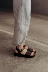 Sandalias negras de cuero con plataforma baja y hebilla plateada.