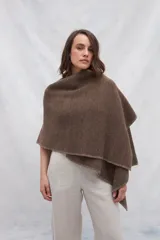 Ruana color crema de tejido de punto industrial con terminación en contraste de color. Tiene doble ojal para mantener el cruce.