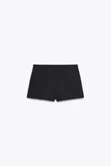 Shorts tiro bajo color negro con bolsillos delanteros. Cierre frontal con cremallera y ganchos metálicos.