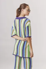 Sweater de tejido crochet a rayas verticales en tonos azul, verde, marrón y blanco, con cuello polo y cierre de botones.