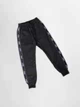 Pantalón de jogging negro con franjas blancas con la palabra "Kaboa" repetida a lo largo de las piernas. Tiene puños elásticos en los tobillos, bolsillos laterales con cierre y cordón ajustable en la cintura.