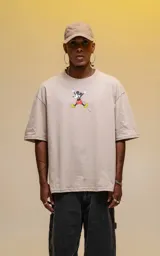 Remera oversize de algodón premium color beige, con cuello redondo y manga corta. Presenta un estampado central de Mickey Mouse en una pose dinámica.