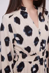 Vestido corto con estampado animal print en tonos beige, negro y azul. Tiene cuello mao, mangas largas con puños elásticos, cintura elastizada y falda con volantes.