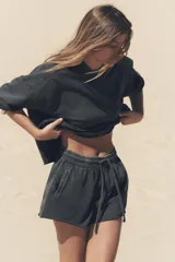 Shorts de tiro alto confeccionados en tejido con efecto lavado, cintura elástica ajustable con cordones, bolsillos laterales de vivo y tejido combinado en rib a tono.