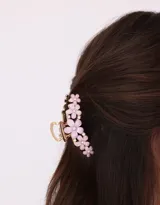 Broche metálico dorado para el pelo con aplique de flores de color rosa claro.