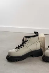 Botas de diseño moderno con suela gruesa, color beige y detalles en negro.