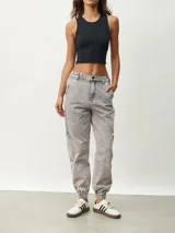 Pantalón jean gris de corte recto, con bolsillos laterales y tobillos ajustados con elástico.