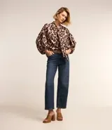 Pantalón de jean de corte recto con cintura alta, color azul oscuro, con bolsillos delanteros y traseros. Se ajusta a la cintura con cinturón de cuero marrón.